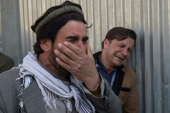 Afghan men weep for their relatives outside the main military hospital in Kabul, on March 8, 2017