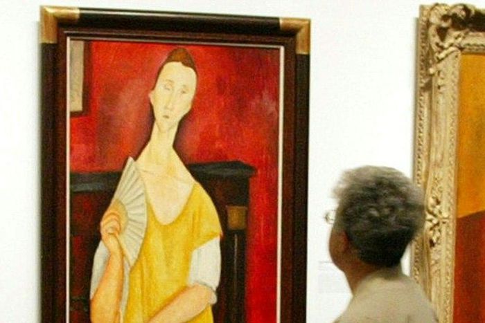 A visitor looks at the painting "Woman with a Fan" by Amedeo Modigliani -- one of five paintings discovered missing on May 20, 2010 at the Paris Musee d'Art Moderne (Modern Art Museum)