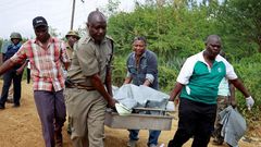 Policemen carry the dead bodies