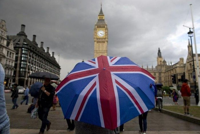 A pedestrian shelters from the rain near the Big Ben clock on June 25, 2016, following the result of the UK's EU referendum vote