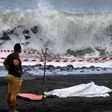 A policeman stands next to the body of a bodyboarder killed by a shark off the Indian Ocean island of Reunion, on February 21, 2017