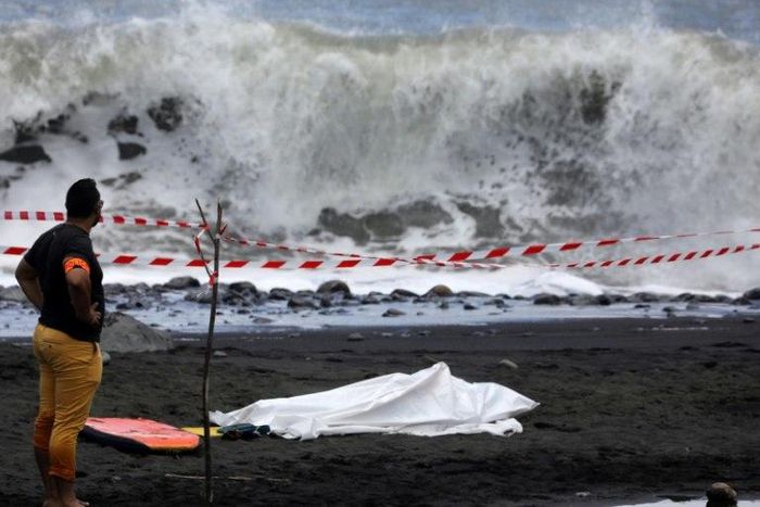 A policeman stands next to the body of a bodyboarder killed by a shark off the Indian Ocean island of Reunion, on February 21, 2017