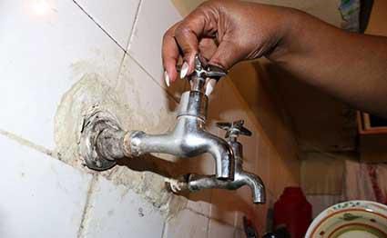 A resident in Nairobi demonstrates empty taps during a past supply disruption