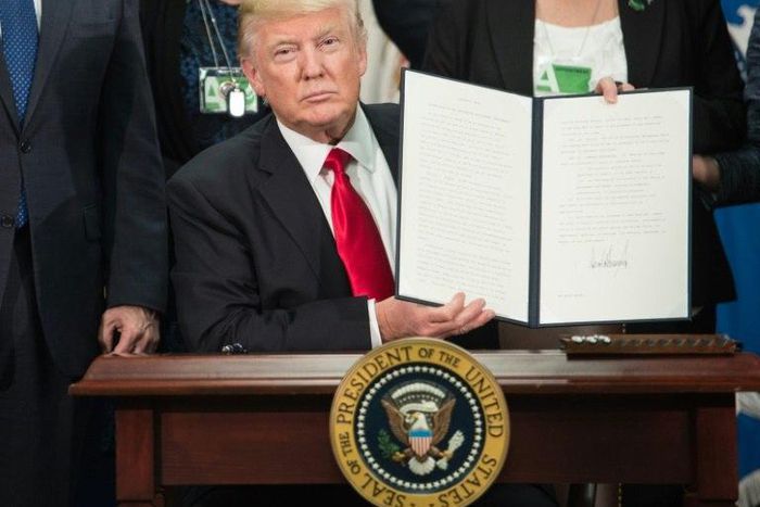 US President Donald Trump signs an executive order to start the Mexico border wall project at the Department of Homeland Security facility in Washington DC, on January 25, 2017