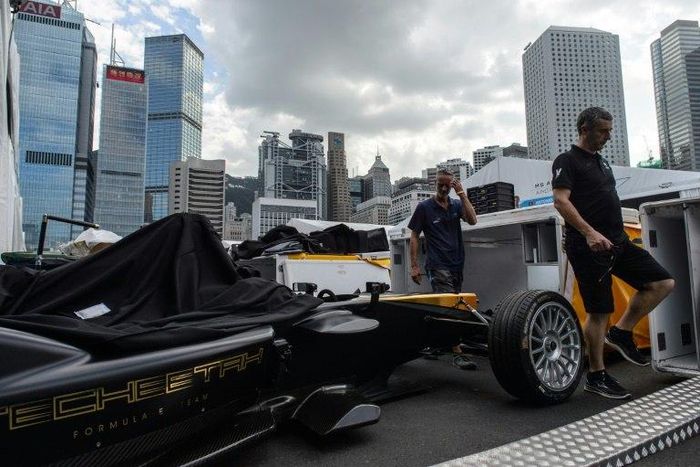 A Techeetah car is seen as other team members walk past in the pit lane of the Formula E track in Hong Kong