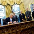 US President Donald Trump signs an executive order alongside officials including National Trade Council Advisor Peter Navarro (3rd R) in the Oval Office of the White House in Washington, DC, on January 23, 2017