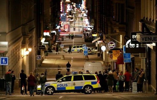 People stand behind a cordon as police work at the scene of a truck attack that killed four people outside a busy department store in central Stockholm on April 7, 2017