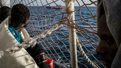 Migrants watch a vessel of the Italian coast guards from the Dutch-flagged rescue ship Sea Watch 3, as 47 migrants including minors, are stranded aboard the vessel anchored off Syracuse, Sicily, on January 26, 2019