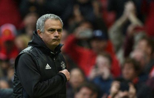 Manchester United manager Jose Mourinho points at the club badge as he leaves the pitch after his side's English Premier League win over Chelsea at Old Trafford in Manchester, north-west England, on April 16, 2017