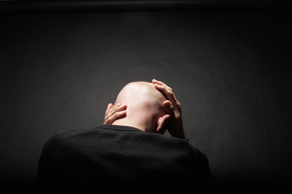 man holding head in hands rear view