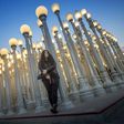 A young woman poses for a picture under "Urban Light" (2008), an assemblage of 202 antique street lamps by Chris Burden, one of LA's most photographed monuments
