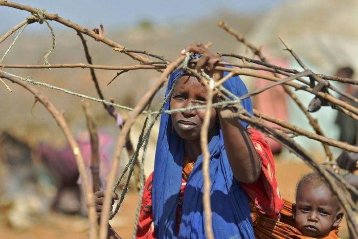 A woman builds a shelter at a makeshift camp on the outskirts of Baidoa, in the southwestern Bay region of Somalia