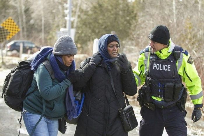An RCMP officer speaks with women from Sudan after they illegally crossed the Canada-US border near Hemmingford, Quebec