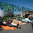 Migrants lay on the ground at the entrance of a migrant and refugee camp near Porte de la Chapelle, northern Paris, on April 19, 2017