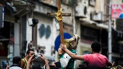 Egyptians raise a wooden cross and palm leaves as they gather outside the Coptic Christian patriarchate in the Mediterranean city of Alexandria where a jihadist bombing killed 17 people