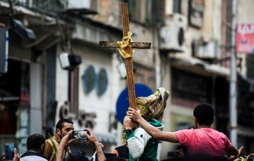 Egyptians raise a wooden cross and palm leaves as they gather outside the Coptic Christian patriarchate in the Mediterranean city of Alexandria where a jihadist bombing killed 17 people