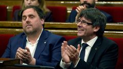 President of the Catalan regional Government Carles Puigdemont (R) and Catalan regional vice-president, Oriol Junqueras applaud after voting the Catalan government's 2017 budget at the Parliament of Catalonia on March 22, 2017 in Barcelona