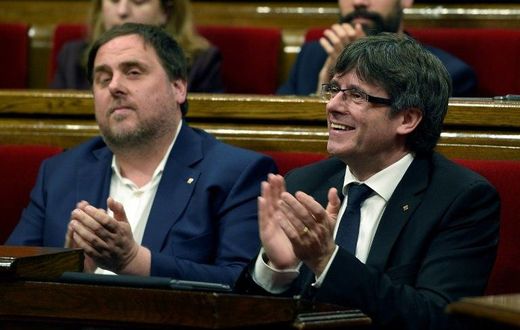 President of the Catalan regional Government Carles Puigdemont (R) and Catalan regional vice-president, Oriol Junqueras applaud after voting the Catalan government's 2017 budget at the Parliament of Catalonia on March 22, 2017 in Barcelona