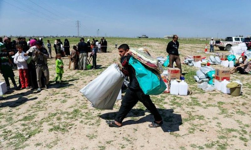 A displaced Iraqi receives humanitarian aid supplies at a camp for the internally displaced, in Salamiyah village east of Mosul, on March 27, 2017