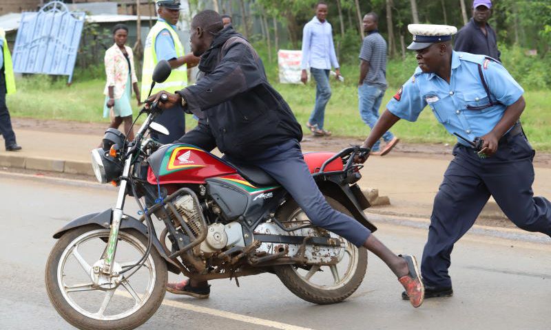 A police officer arresting a boda boda rider