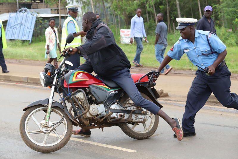 A police officer arresting a boda boda rider