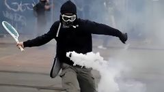 A protester smacks away a tear gas canister thrown by police officers during the anti-Finance Bill protests in Nairobi on June 18, 2024.