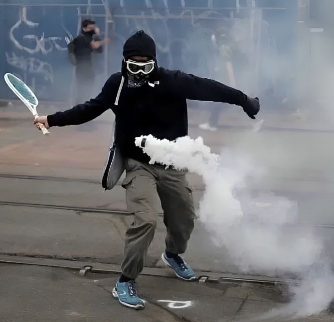A protester smacks away a tear gas canister thrown by police officers during the anti-Finance Bill protests in Nairobi on June 18, 2024.