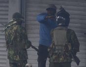 Police officers confront city hawker in Nairobi during protests