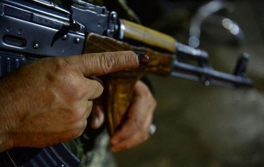 A security guard shows his finger marked with ink as he holds a weapon after casting his vote in Afghanistan's presidential elections. Initial data suggests turnout at a record low