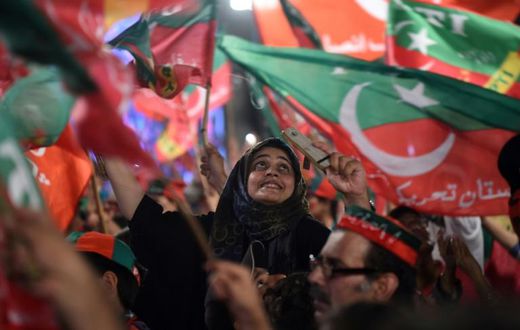 Pakistan Tehreek-e-Insaf supporters wave party flags during campaigning that brought Imran Khan to power in July 2018