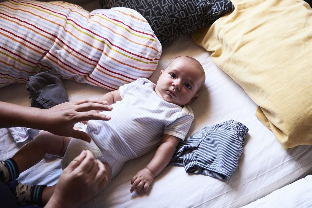 Little boy getting changed at home by mother