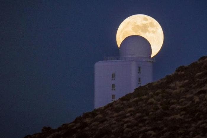 (FILES) In this file photo taken on December 13, 2016 the full moon is seen behind a telescope of the Spain's Institute of Astrophysics of the Canary Islands, in the National Park of El Teide, on the Spanish canary island of Tenerife on December. A tea...