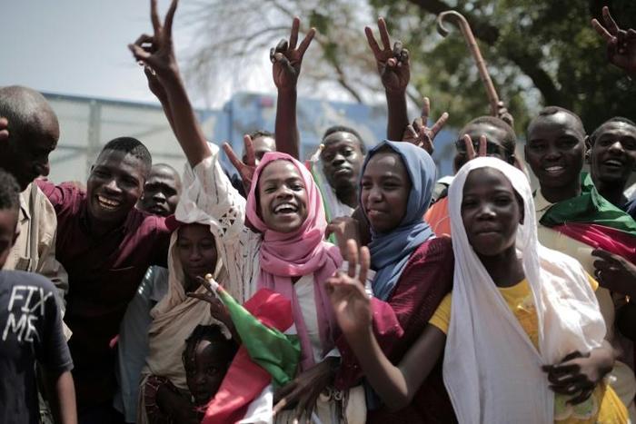 Sudanese citizens celebrate outside the Friendship Hall in Khartoum where generals and protest leaders on Saturday signed a historic transitional constitution meant to pave the way for civilian rule