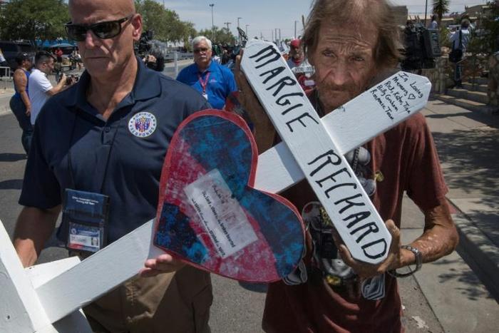 Antonio Basco (R) holds the cross of his common-law wife Margie Reckard who died in the El Paso shooting, as he walks to a makeshift memorial after the shooting that left 22 people dead