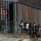 Central American migrants look through a border fence as a US Border Patrol agent stands guard near Tijuana, Mexico: people who cross the border illegally will have their DNA collected by US officials in the future