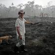 Brazilian farmer Helio Lombardo Do Santos and a dog walk through a burnt area of the Amazon rainforest, near Porto Velho, Rondonia state, Brazil, on August 26, 2019