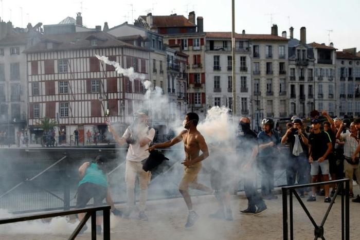 A protester lobs a tear gas canister back at French police during an anti-G7 rally in the southwestern French city of Bayonne