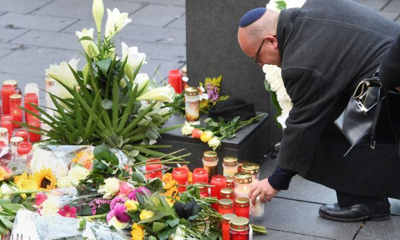 A man wearing a kippah skullcap places a candle at a makeshift memorial a day after two people were shot dead as Halle's Jewish community marked Yom Kippur
