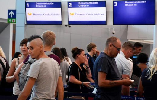 Passengers stand in line at the closed Thomas Cook check-in desk at the airport in Cancun, Mexico, on September 23, 2019