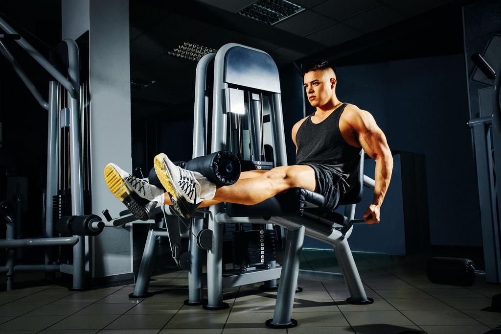 Strong young man doing legs exercise in the gym