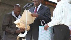 File image of DP Ruto holding cash donations at a past harambee