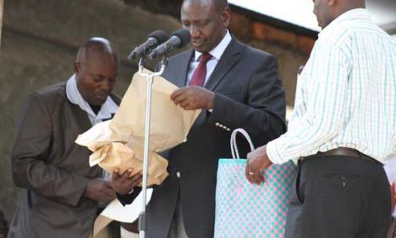 File image of DP Ruto holding cash donations at a past harambee