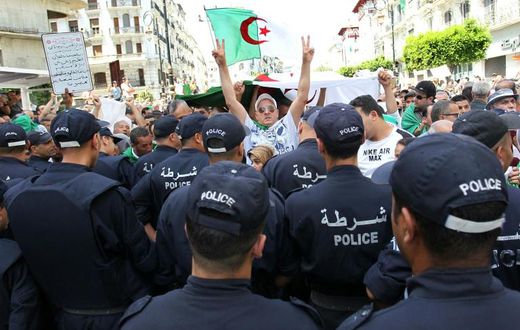 Algerian protesters face riot police during a demonstration in the capital Algiers in June