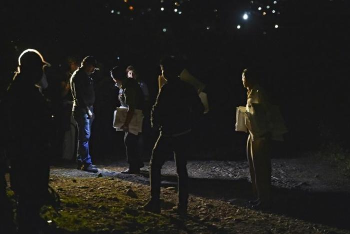 Police and forensic personnel holding white bags for corpses stand by an unmarked grave in 2014 in Guerrero state, Mexico -- a country that has suffered a wave of violence since launching the so-called "drug war"