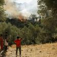 Refugees and migrants look at a fire that broke out in the camp of Moria in Mytilene on September 29, 2019