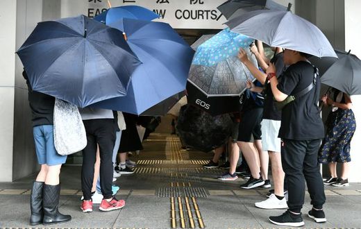 Protesters covered themselves with umbrellas as they gathered outside the Eastern District Courts in Hong Kong