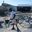 Irvin Russell carries the Bahamian flag as he walks past a damaged truck on Treasure Cay in the hurricane-hit Bahamas