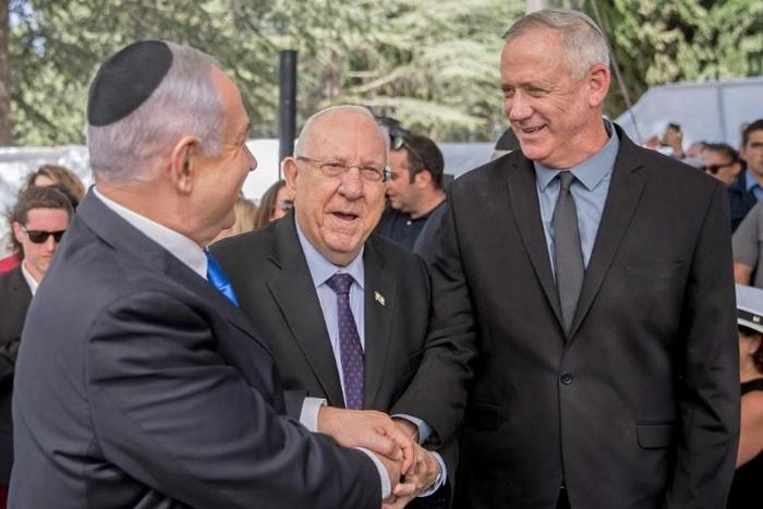 Israel President Reuven Rivlin watches on as opposition leader Benny Gantz shakes hands with Prime Minister Benjamin Netanyahu hours before laying claim to his job