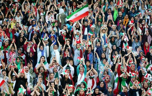 Wearing sporty hats and the national flag, Iranian women cheer for their team at a game they will never forget.