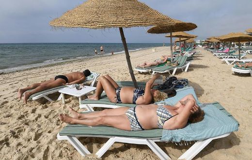 Tourists sunbathe on a private beach near a hotel in Tunisia's Nabeul on July 1, 2018